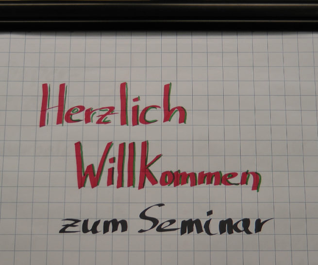 Flipchart mit dem Texte "Herzlich Willkommen zum Seminar"